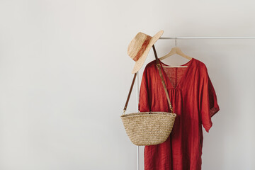 Women's fashion clothes and accessories. Stylish female straw handbag, straw hat, red dress on...