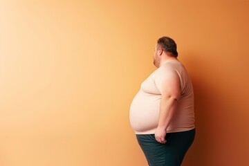 Fat man with overweight on a orange background. The concept of diet and weight loss. Overweight and obesity concept. Obesity Concept with Copy Space.