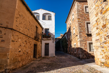 Narrow alley with old houses next to the wall of the medieval city of Caceres
