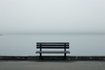 Fototapeta na wymiar A lone wooden bench sits in the fog, overlooking the calm lake as the sky reflects on its glassy surface, creating a serene and peaceful landscape