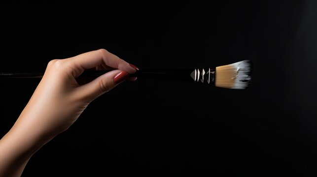 A woman artist is demonstrating how to paint on her canvas with a brush in front of a black background.