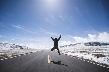Asian woman jumping on high altitude country road - obrazy, fototapety, plakaty