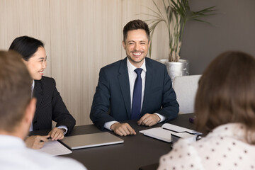 Happy joyful multiethnic colleagues having fun on teamwork meeting, talking on common project, laughing at jokes, relaxing, brainstorming. Positive diverse business partners discussing collaboration
