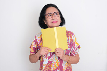 Elderly Asian woman thinking about something while holding a book