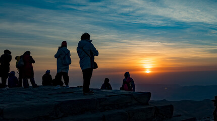 Silhouette of people at sunrise on a mountain top.