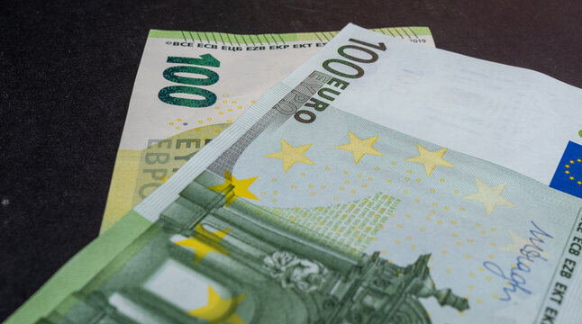 Close-up high quality photo of a 100 Euro banknote isolated on a black background. Euro banknotes, inflation and price increases. Savings and investment. Earning money.