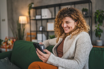 One woman with curly hair at home use mobile phone smartphone sms texting or browse internet