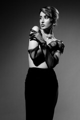 Naklejka premium Beautiful luxury young woman with clean skin covering her nude breast. Studio grey background monochrome