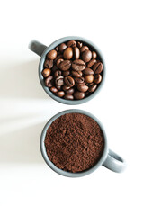 Due tazze di caffè grigie con chicchi di caffè e caffè macinato isolati su sfondo bianco. Vista dall'alto. Copia spazio.