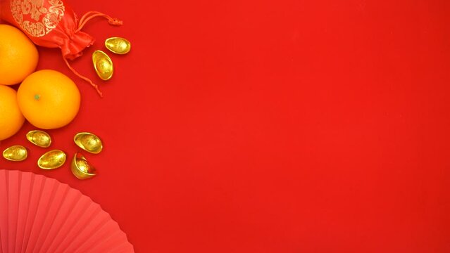 flat lay looping footage of hand holding Tae Eia envelope (red envelope) out from the top for giving money during Chinese Lunar New Year celebration red background with lucky item decoration ornament