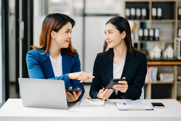 Two Asian businesswoman discuss investment project working and planning strategy with tablet laptop computer