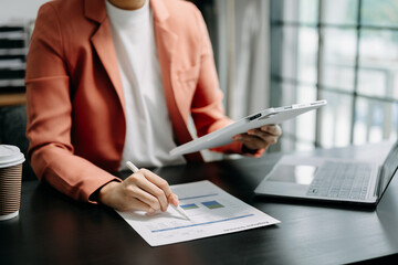 business documents on office table with smart phone and digital tablet and graph financial and woman working .