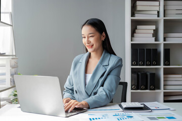 Young happy businesswoman using computer in office, Stylish Beautiful Manager Smiling, Working on Financial and Marketing Projects, Portrait of a young businesswoman working on a laptop in an office