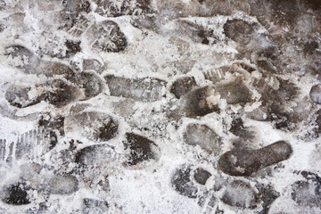 Bad winter pavement condition. Muddy footpath. Shoes imprints. Wet snow melting. Sidewalk covered with wet snow. Danger of slippery. Footprints texture. Slush on ground.