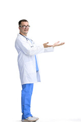 The male doctor, on a white background, in full height, points to the side