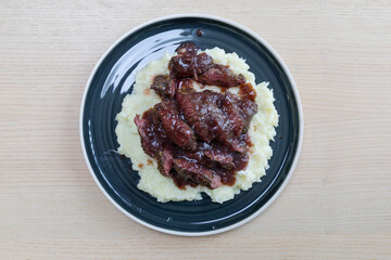 A plate of steak with red wine sauce and mash potato.