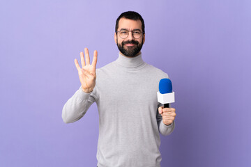 Naklejka premium Adult reporter man with beard holding a microphone over isolated purple background happy and counting four with fingers