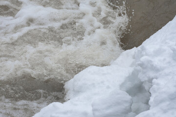 The end of winter. Stormy flow of water in a mountain river, close up.