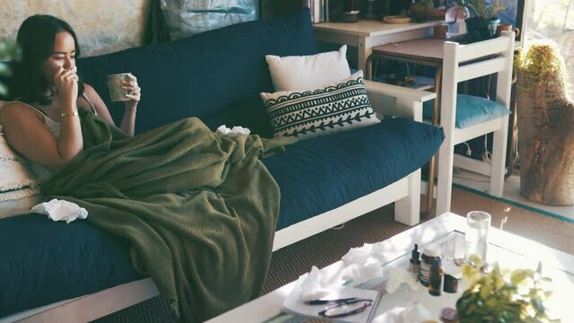 Woman, sick and blowing nose in couch, cup and virus for infection, sinus and cold symptoms. Sneeze, living room and allergy with hayfever, medical and healthcare for disease and spread germs