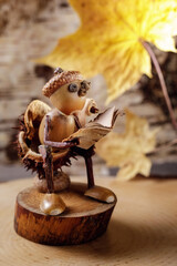 Natural materials for children's creativity. Gnome figurine with book made of acorns and cones, easy autumn goods craft.
