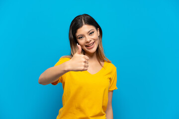 Young Russian girl isolated on blue background with thumbs up because something good has happened