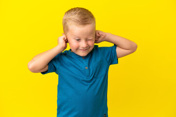 Little Russian boy isolated on yellow background frustrated and covering ears