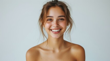 Obraz premium Close up portrait of a beautiful young woman with flawless skin smiling at the camera