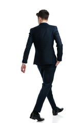 elegant businessman looking to side and walking with hand in pocket
