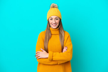 Young caucasian woman wearing winter jacket isolated on blue background keeping the arms crossed in...