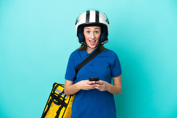 Young caucasian woman with thermal backpack isolated on white background surprised and sending a message