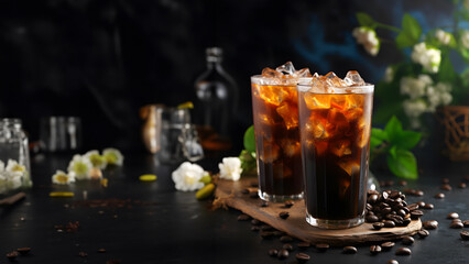 Two glasses of iced Americano on a black background and jasmine flowers