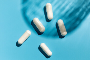 White capsules with vitamins or a dietary supplement on a blue background. Medicine, medicines