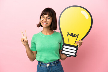 Youing woman holding a bulb icon and celebrating a victory