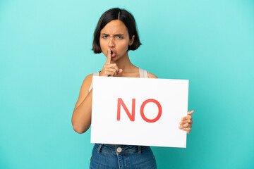 Young mixed race woman isolated on blue background holding a placard with text NO doing silence...