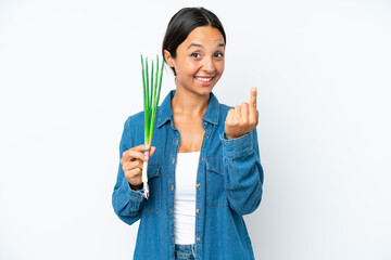 Young hispanic woman holding chive isolated on white background doing coming gesture