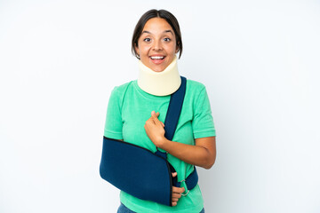 Young hispanic woman wearing a neck brace and sling isolated on white background with surprise...
