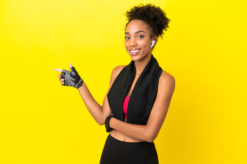 Young African sport woman isolated on yellow background pointing finger to the side