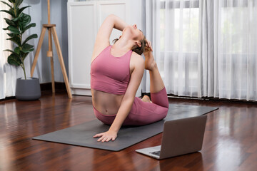 Flexible and dexterity woman in sportswear doing yoga position in meditation posture on exercising...