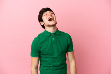 Young Russian man isolated on pink background laughing