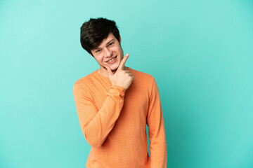 Young Russian man isolated on blue background happy and smiling