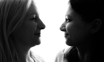 Silhouette mother and daughter looking at each other on white background.