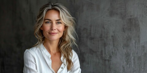 Fototapeta premium Cheerful and confident mature woman exuding natural beauty and elegance in a studio portrait.