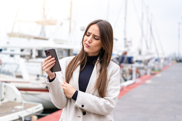 Young pretty woman using mobile phone at outdoors with sad expression