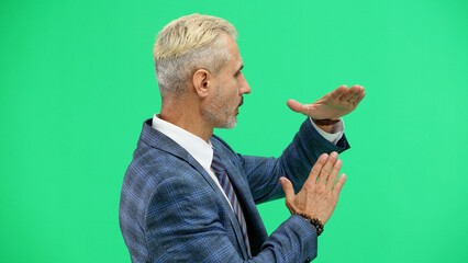 A man, close-up, on a green background, shows a pause sign