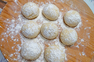 Small round pieces of dough on a wooden board.