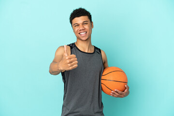 Basketball player African American man isolated on blue background with thumbs up because something...
