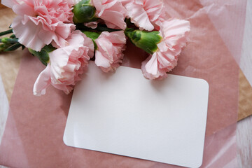Beautiful pink and white carnation flower and blank card composition on wooden background. Flower background for Mother's day, Women's day and anniversary design.