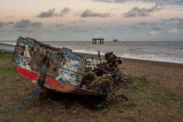 Obraz premium A shipwreck on the beach and offshore platforms in the background, seen in Sizewell, Suffolk, England, UK