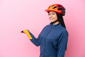 Teenager cyclist girl isolated on pink background extending hands to the side for inviting to come - obrazy, fototapety, plakaty