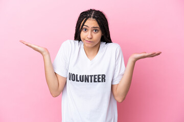Teenager volunteer girl with braids isolated on pink background having doubts while raising hands